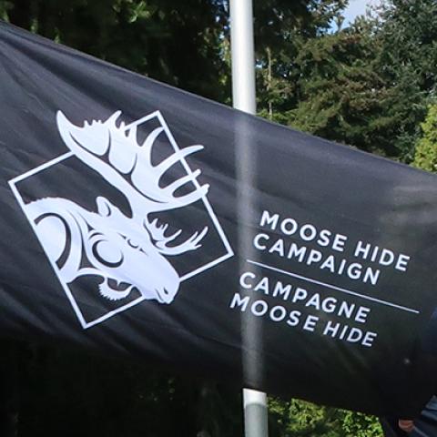 Black flag with white moose logo and lettering saying Moose Hide Campaign.