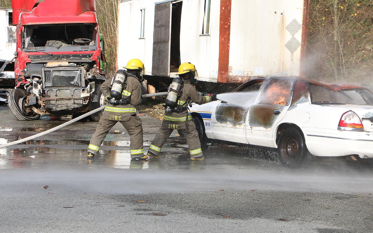 FFTC grad Lindsay Anderson, right, takes the lead while demonstrating putting out a car fire at JIBC's Maple Ridge campus.