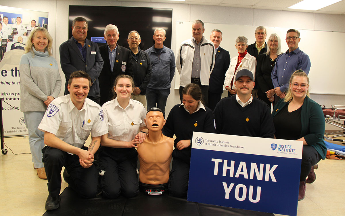 JIBC Paramedic students pose with members of the Chilliwack Foundation, and a training mannikin and a "Thank You" sign.