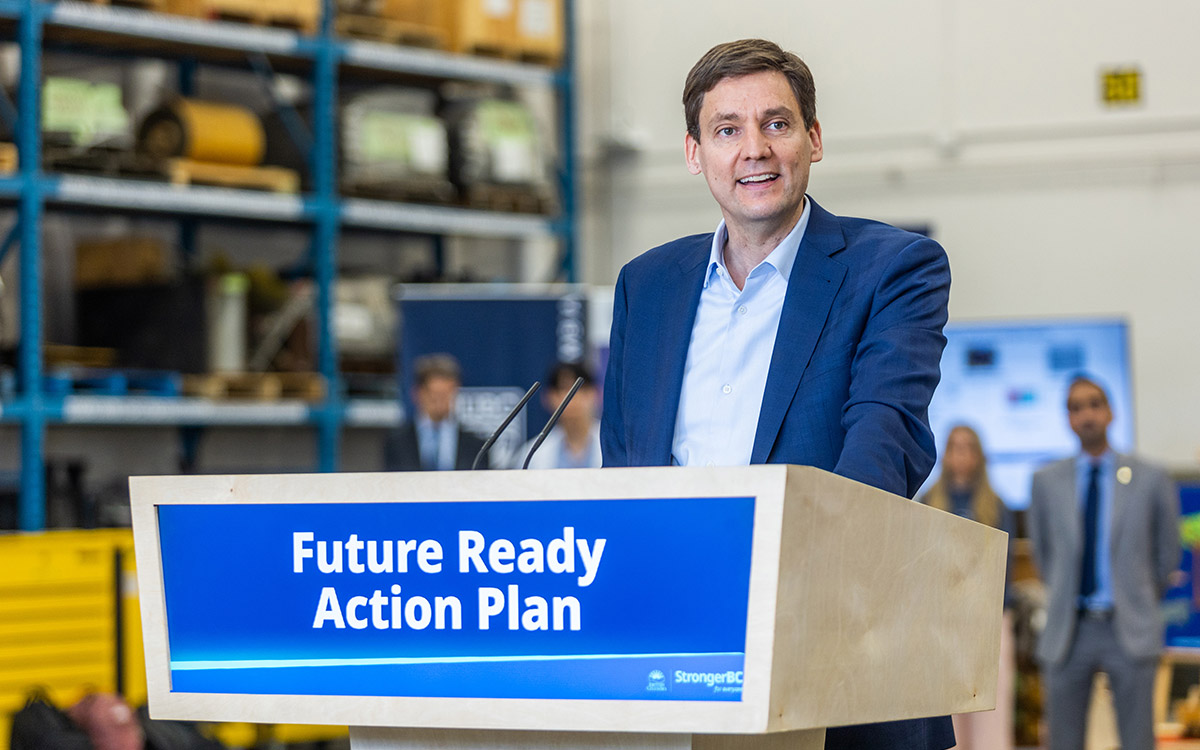 B.C. Premier David Eby stands smiling at podium that reads "Future Ready Action Plan."