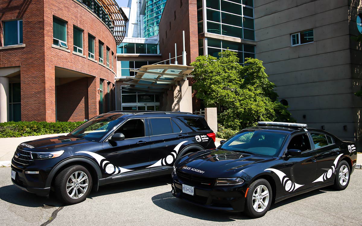 Two JIBC Police Academy training vehicles sit side by side sporting its new Indigenous artwork at New Westminster campus.