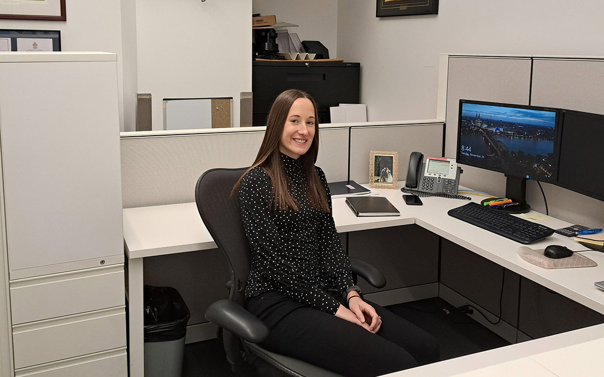 Woman sits at desk in front of computer.