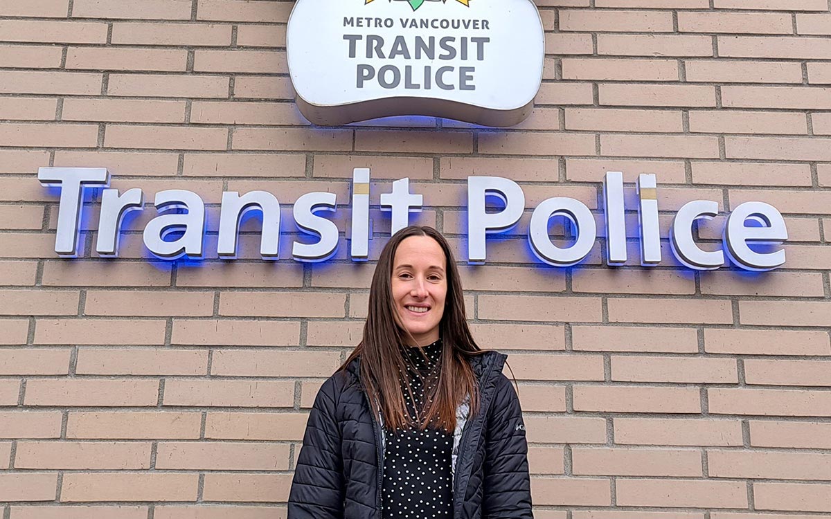 Woman stands in front of Metro Vancouver Transit Police sign.