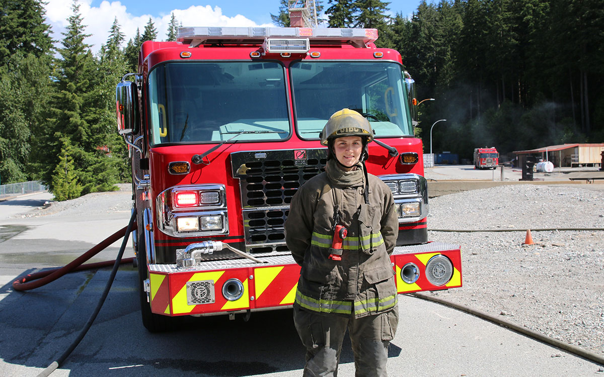 Firefighting student Mackenzie Millward stands in front of fire truck at JIBC's Maple Ridge campus.