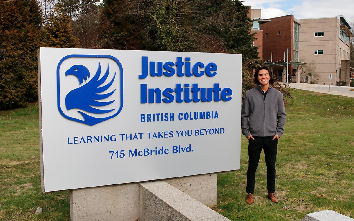 Man stands next to JIBC sign at entrance to New Westminster campus.