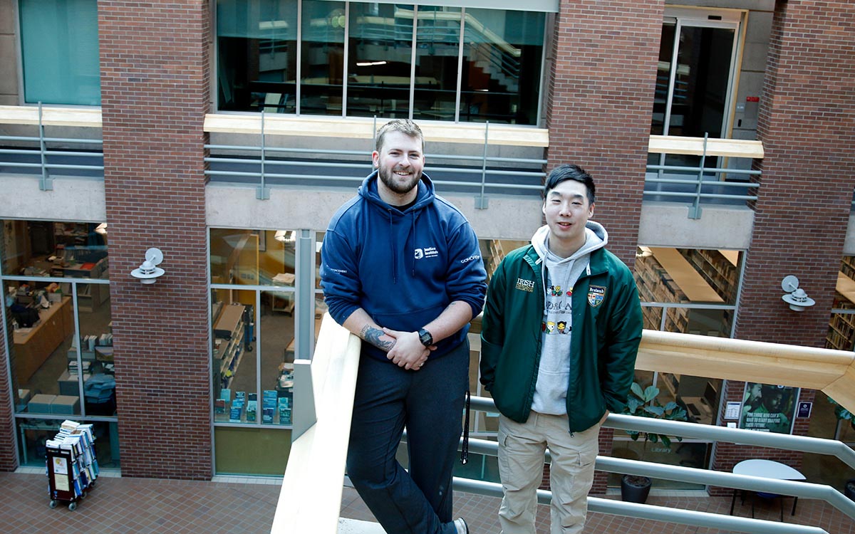 Two male students stand on landing overlooking atrium at New Westminster campus.
