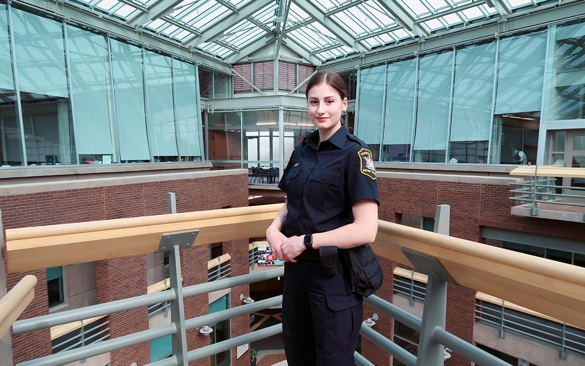 Woman in black BC Corrections officer uniform stands overlooking atrium at JIBC's New Westminster campus.