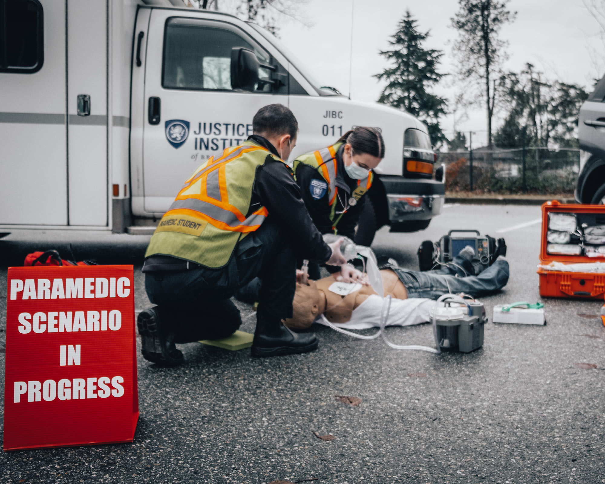 Two paramedic students work on a dummy on the pavement in a scenario training exercise.