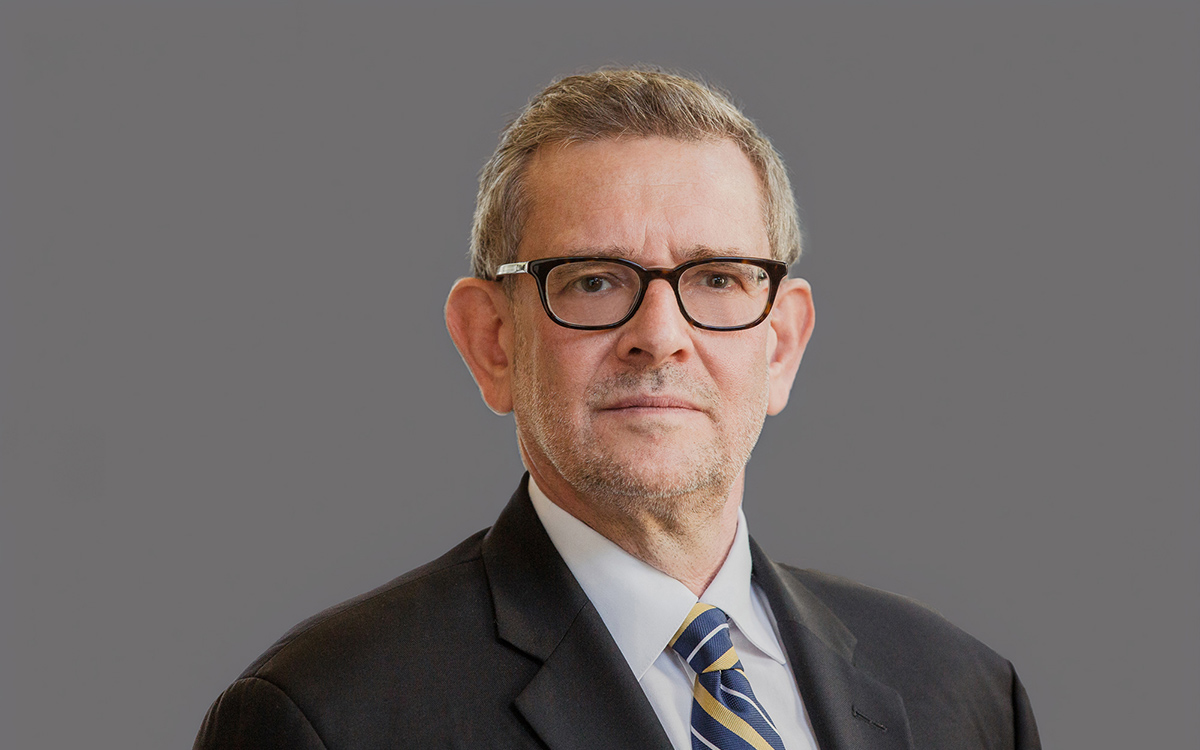 Head and shoulders image of man wearing dark suit and glasses.