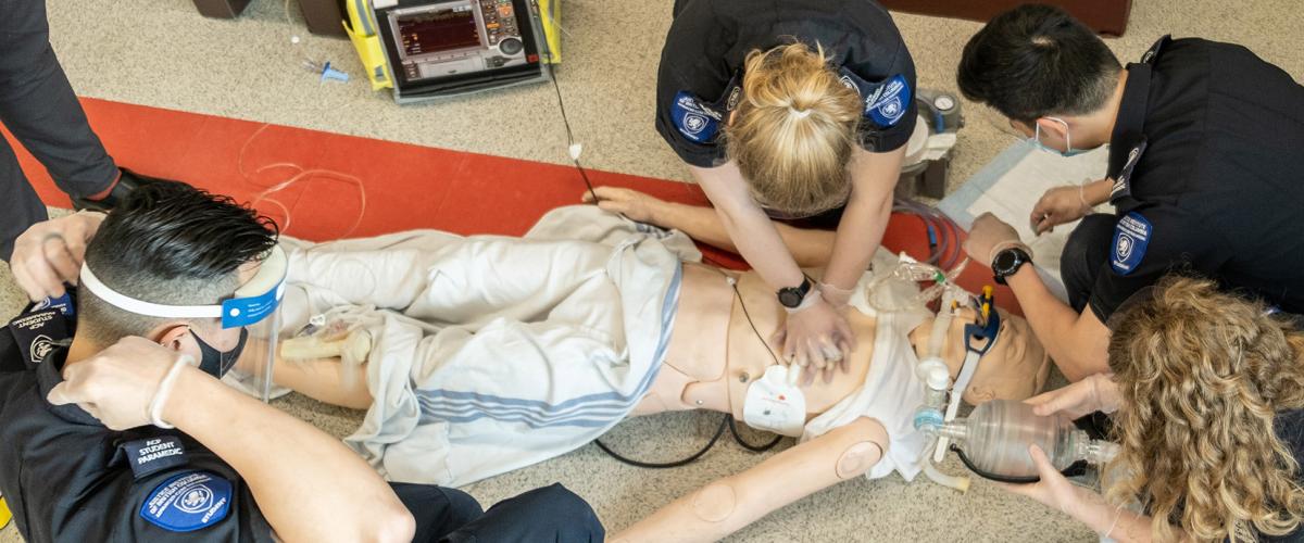 Overhead shot of Advanced Care Paramedic students practising CPR on a mannikin.