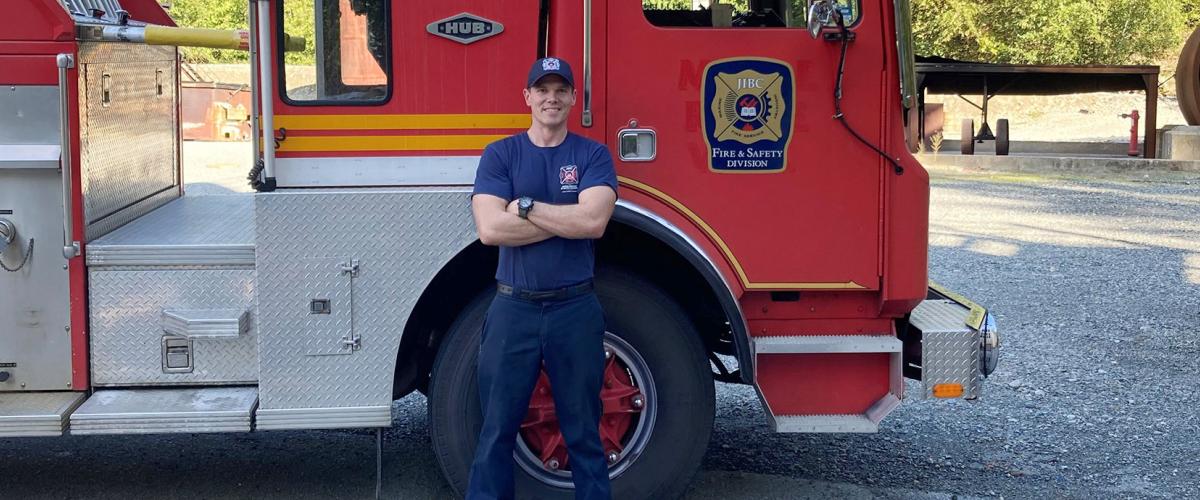 FFTC grad Jesse Fryer in front of fire truck at JIBC Maple Ridge campus.