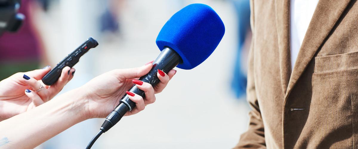 Microphone held in front of person wearing brown jacket.