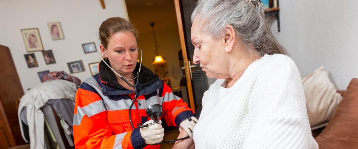 Paramedic checking blood pressure of elderly woman.