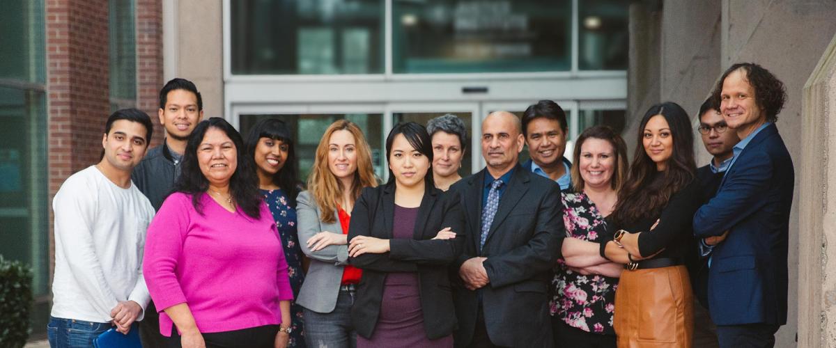 Diverse group of people stand in front of building.
