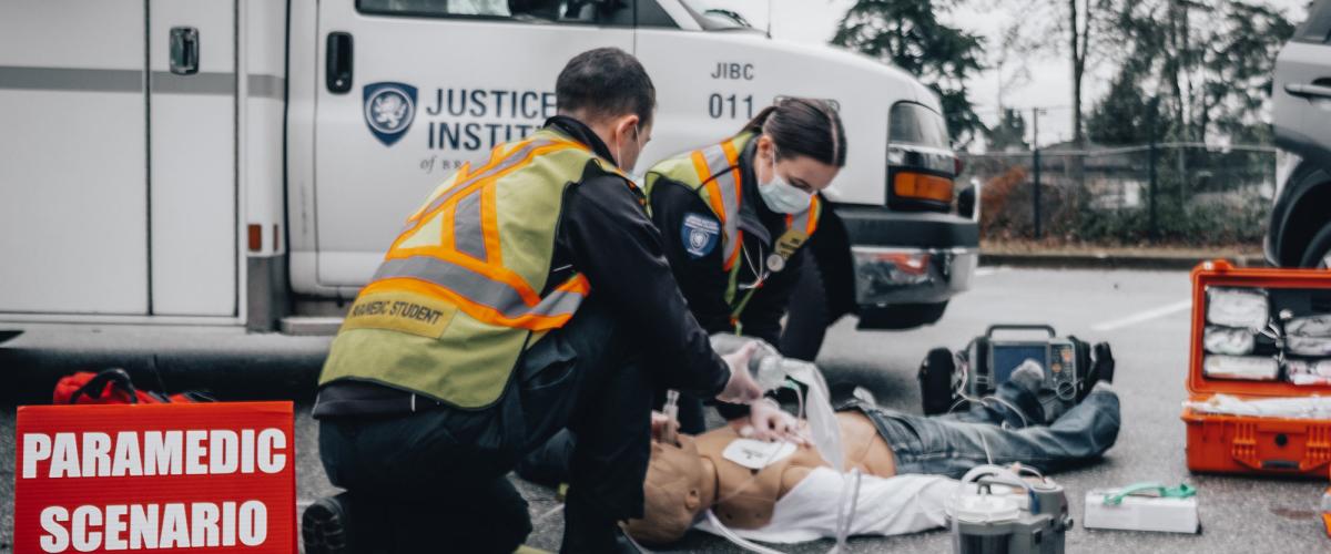 Two paramedic students work on a dummy on the pavement in a scenario training exercise.