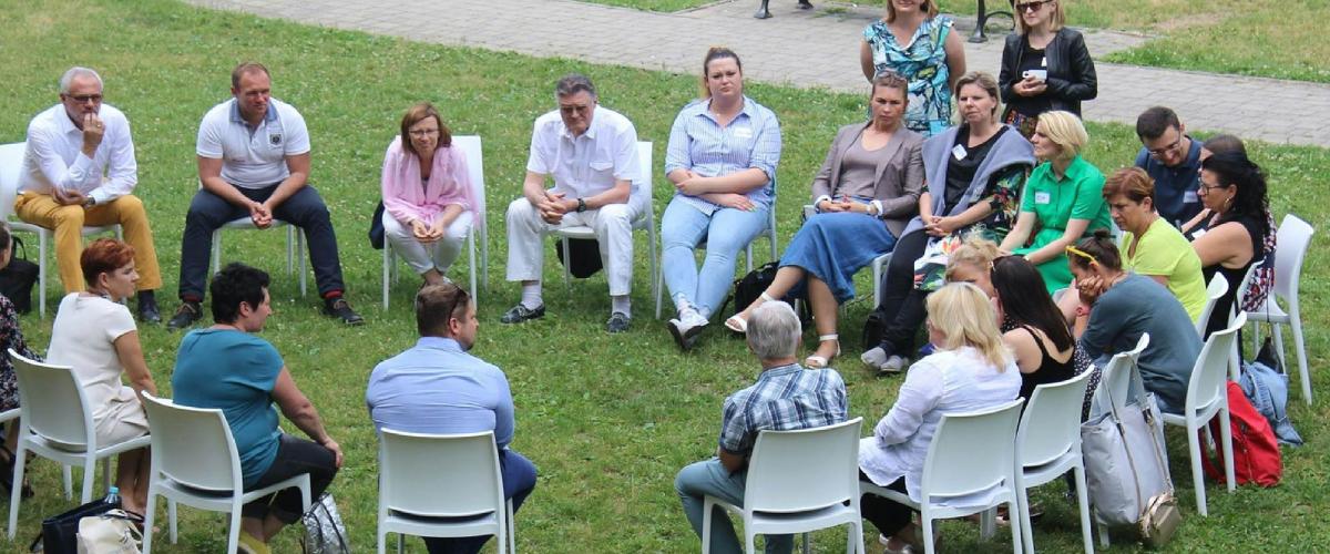 Group of people seated in chairs in a circle outdoors.
