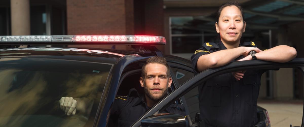 Two police officers posing beside a police car