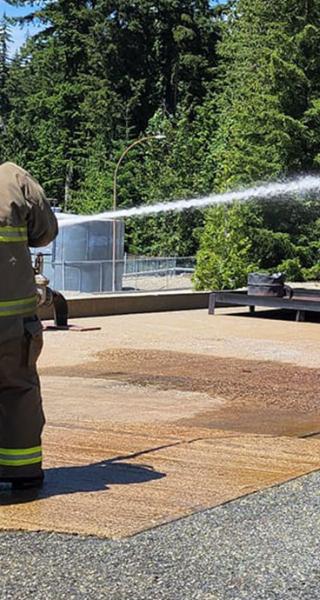 Participants in Indigenous Youth Career Camp at JIBC learn to use a fire hose at the Maple Ridge campus.