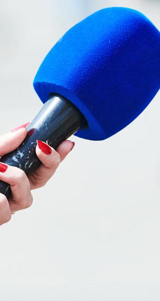 Microphone held in front of person wearing brown jacket.
