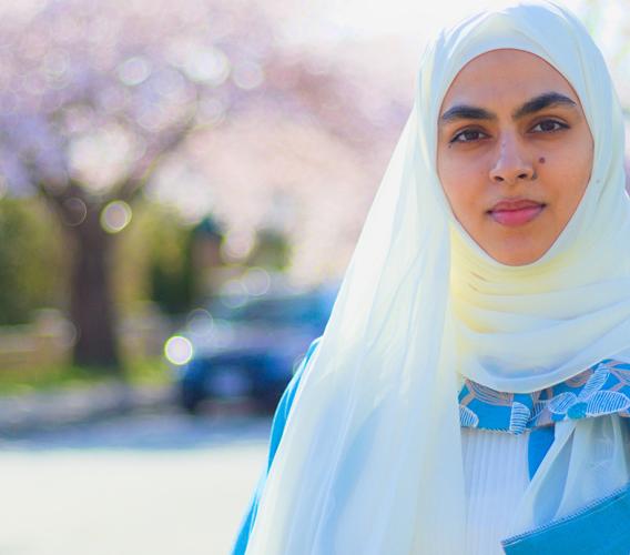 Mona Zafar standing on street lined with cherry blossom trees.