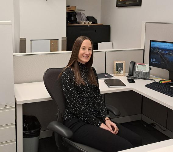 Woman sits at desk in front of computer.