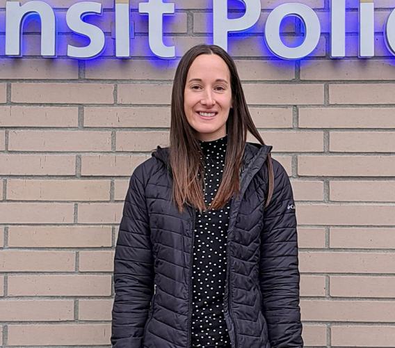 Woman stands in front of building where sign reads "Transit Police"