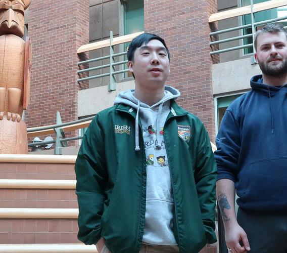 Two male students in atrium at JIBC's New Westminster campus, with Welcome Post in the background.