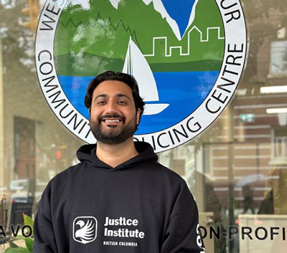 Man wearing black JIBC hoodie in front of community policing centre.