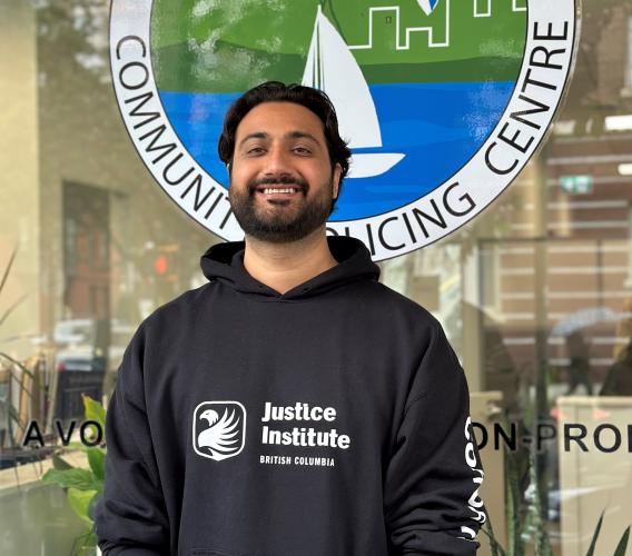 Man wearing black JIBC hoodie in front of community policing centre.