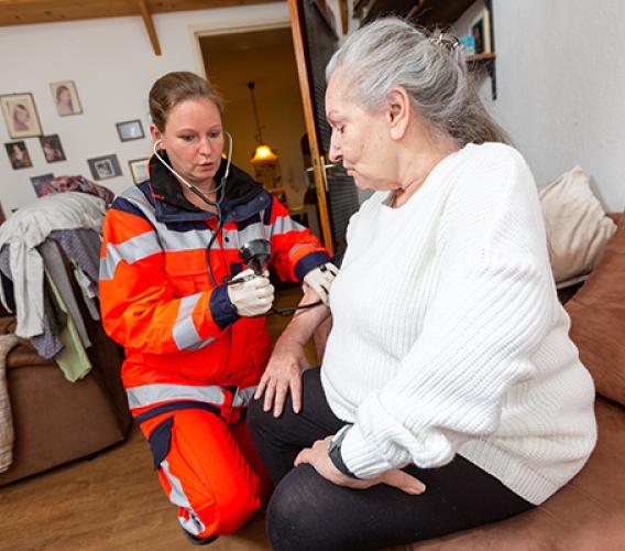 Paramedic checking blood pressure of elderly woman.