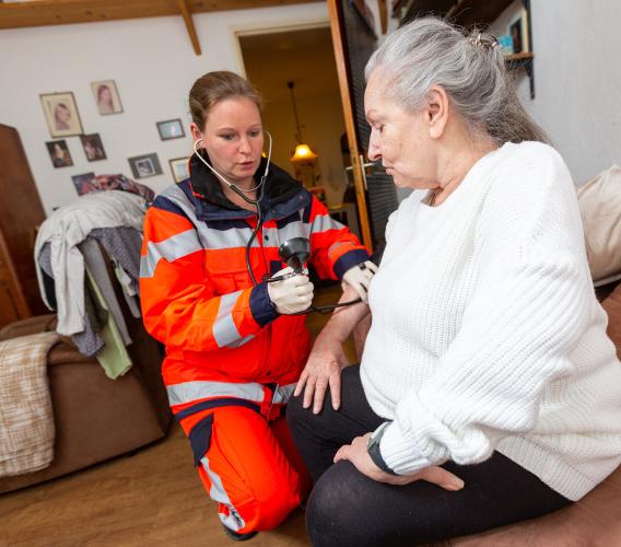 Paramedic checking blood pressure of elderly woman.