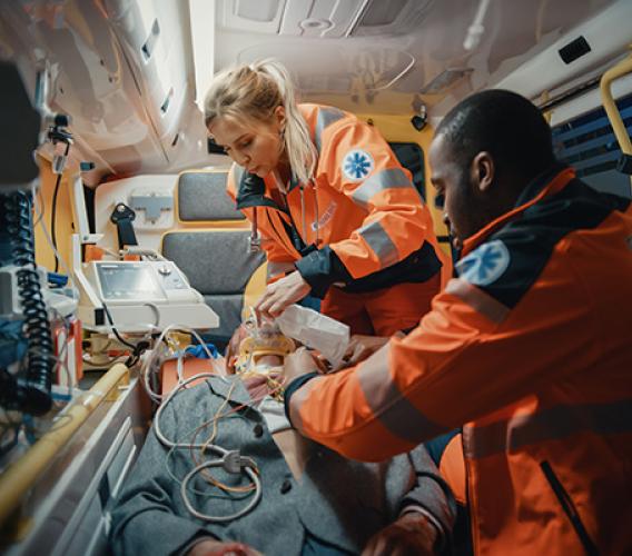 Two paramedics treat a patient inside ambulance.