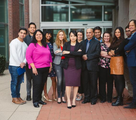 Diverse group of people stand in front of building.