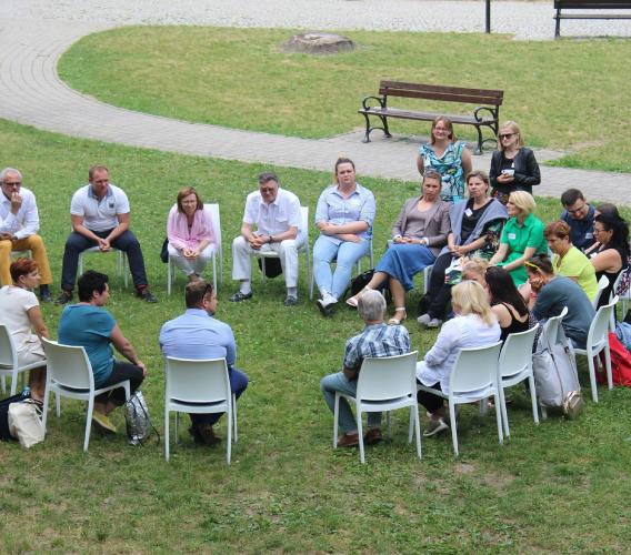 Group of people seated in chairs in a circle outdoors.