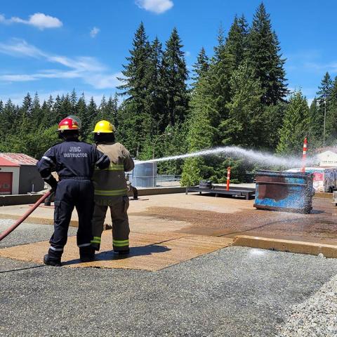 Participants of the JIBC Indigenous Youth Career Camp learn the basics of using a fire hose at the Maple Ridge campus.