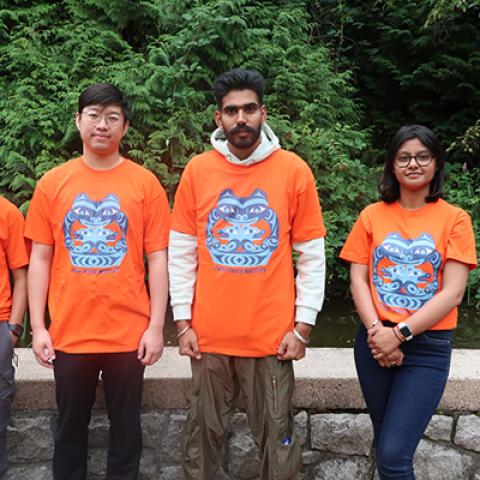 Three men and one woman wearing orange t-shirts.