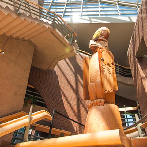 Carved wooden welcome post in bright atrium. 