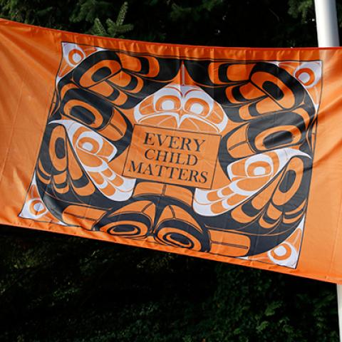 Orange flag of Indigenous design with "Every Child Matters" in the centre.