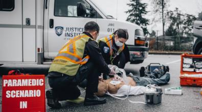 Two paramedic students work on a dummy on the pavement in a scenario training exercise.