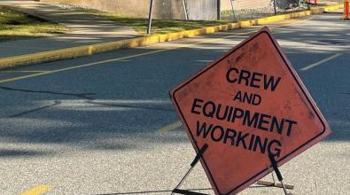 Construction sign reading crew and equipment working