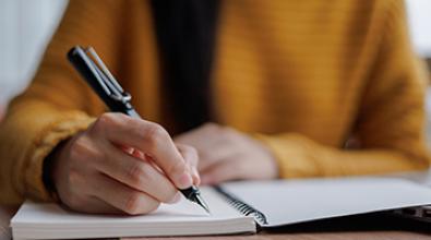 women writing on a white notepad