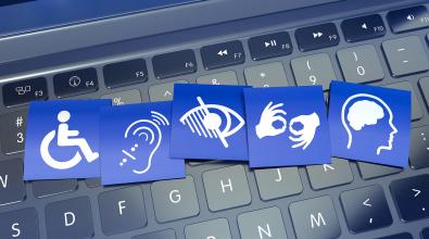 Blue cards with symbols of accessibility needs on top of black keyboard.
