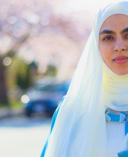 Mona Zafar standing on street lined with cherry blossom trees.