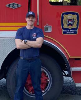 FFTC grad Jesse Fryer in front of fire truck at JIBC Maple Ridge campus.