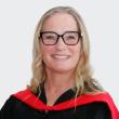 Woman with black-rimmed glasses wearing black convocation gown.