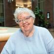 Grey-haired woman wearing glasses and light blue sweater.