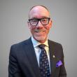 Man with glasses wearing dark suit and tie.