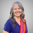 Woman wearing dark blue top with red Metis sash over her left shoulder..