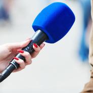 Microphone held in front of person wearing brown jacket.