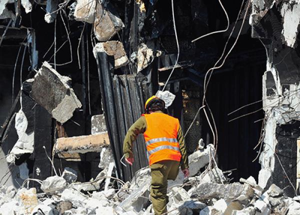 Man standing in front of a destroyed building 